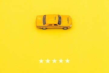 Yellow toy car Taxi Cab and 5 stars rating isolated on yellow background. Smartphone application of...