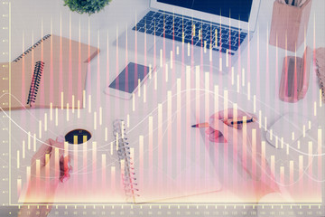 Hands writing information about stock market in notepad. Forex chart holograms in front. Concept of...