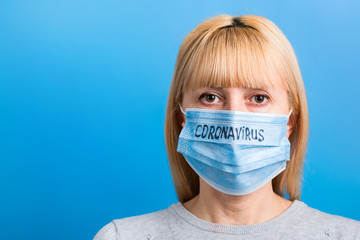 Portrait of woman wearing medical mask with coronavirus text at blue background. Coronavirus...