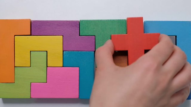 Closeup Slow motion. Hand holding piece of wooden block puzzle. wood cube stacking. Concept of complex and smart logical thinking.