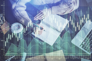 Forex graph on hand taking notes background. Concept of research. Double exposure