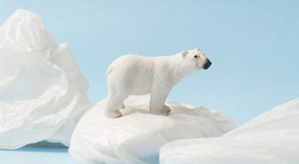 Fototapeta na wymiar White polar bear on plastic bag on blue background, plastic pollution and climate change concept