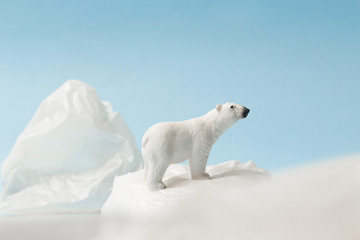 Obraz na płótnie Canvas White polar bear on plastic bag on blue background, plastic pollution and climate change concept