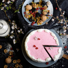 homemade cake with cherries and dried fruits on a black background shot from above among the ingredients