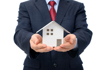 Businessman with house model on hand. Real estate concept. Isolated on a white background.
