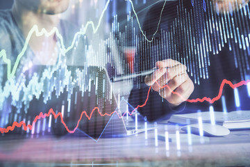 Forex graph with businessman typing on computer in office on background. Concept of analysis. Double exposure.