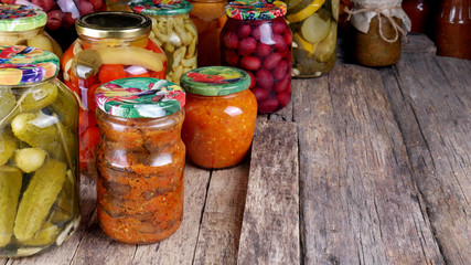 Glass jars with canned products - vegetables and fruits on an old wooden flooring. The concept of farming and homestead agriculture.