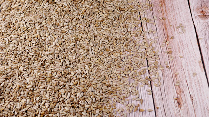 A lot of peeled sunflower seeds on a wooden table close-up. Place for text.