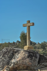 Detailed view at the stone crucifix sculpture, blue sky and field of trees on background