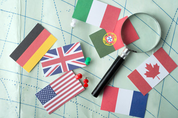 Top view of magnifuing glass, differents flags, pins on the worl map.Concept of traveling various countries