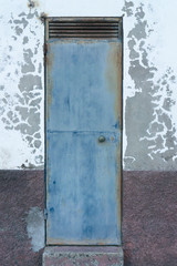 Old gray metal door from an old house where the plaster is peeling off