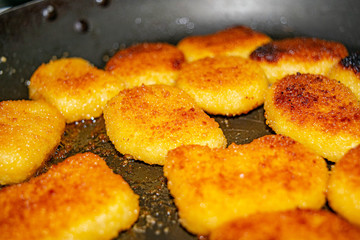 Chicken nuggets are fried in a pan. Close up.