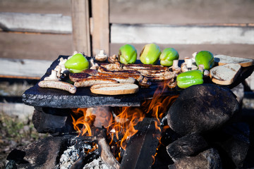 grilled sausages and bread on the fire on the coals in the Park with skewers