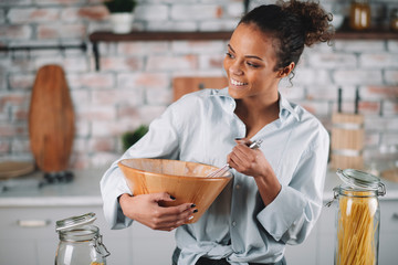 Beautiful woman in kitchen. Mixed race woman making cake. 