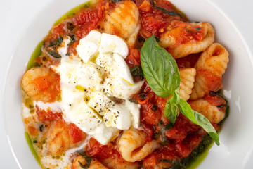 Traditional italian pasta. Italian potato dumplings gnocchi alla sorrentina with mozzarella cheese. Parmesan and mozzarella cheese sauce dressing. Restaurant table setting.