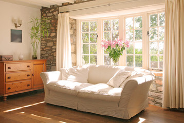 stone cottage interior lounge with with sunshine streaming through window - obrazy, fototapety, plakaty