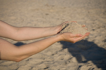 Fototapeta na wymiar close-up of hands with sand falling on a beach