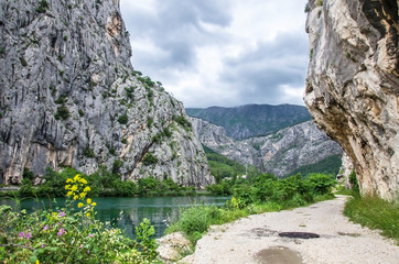 Fototapeta na wymiar Gravel road through mountains near river, Omis, Croatia