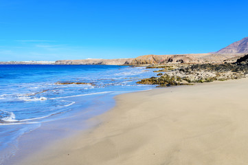 View of beautiful Papagayo beach near town named Playa Blanca, Lanzarote, Canary Islands. View of blue sea, yellow sand, selective focus