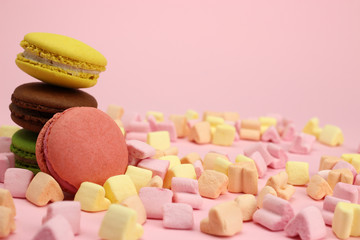 Colored macaroons or macarons, marshmallow hearts on a pink background