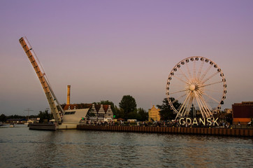 View of Ferris Wheel and lifted Footbridge over Motlawa during sunset. Gdańsk (Danzig in German) is a port city on the Baltic coast of Poland.