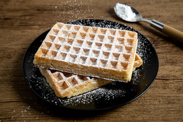Sugar waffles presented on a black plate