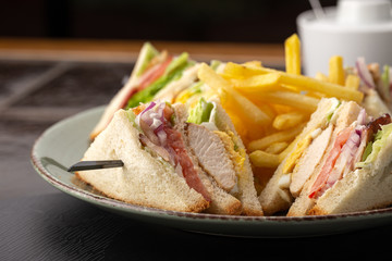 Juicy sandwich on wooden table. Delicious fastfood grilled fresh tasty sandwich. Tasty home made sandwich with meat, tomato, cheese, bacon and lettuce. sandwich with fries and different sauces.