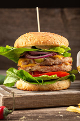 Juicy bacon burger on wooden table. Delicious fastfood grilled fresh tasty burger. Tasty grilled home made burger with beef, tomato, cheese, bacon and lettuce. Hamburger with fries and different sauce