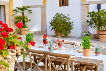 Fototapeta na wymiar Mesa decorada con tomates y plantas en patio mediterráneo