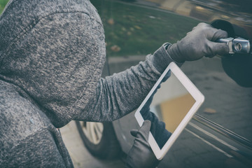 Hooded thief tries to break the car's security systems with tablet