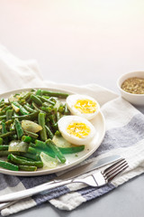Fried wok green beans with egg, onions and spices in a white plate on a gray background. Flat lei. Top view. Copy space