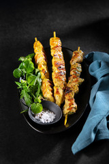 Grilled chicken and pork Curry Skewers, kebabs with spices, herbs on dark background, copy space. Keto Paleo. Pegan Diet.