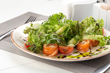 Delicious fresh salad. Salad with salmon, mozzarella cheese, cherry tomatoes, arugula, olive oil. Fresh salmon salad with mozzarella and vegetables. Close up view on Salad. Healthy, diet tasty summer 