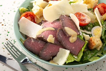 Delicious fresh salad. Caesar salad. Caesar salad with fresh lettuce, parmesan, fried croutons, roast beef. Restaurant food, close up. Meat salad. Close up view.