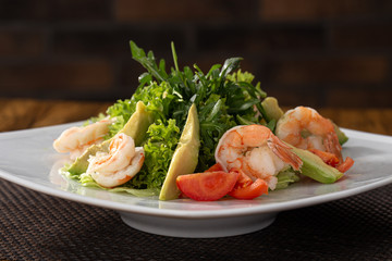 Delicious fresh salad. Shrimp salad, lettuce, arugula, olive oil, cheese, parmesan. fresh healthy avocado and shrimps salad. Close up view on Salad. Healthy, diet tasty summer dish