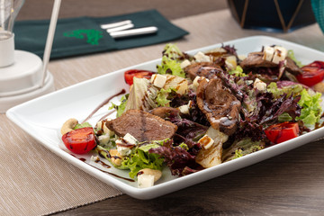 Delicious fresh salad. Duck breast fillets steak salad with tomatoes, cheese, lettuce, olive oil. Close up view on Salad. Healthy, diet tasty summer dish