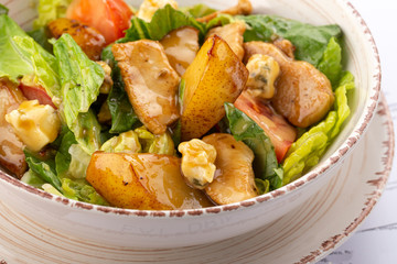 Delicious fresh salad. Plate of fresh salad with grilled chicken, pear, cheese and nuts covered with herb honey dressing. Restaurant food, close up. Meat salad. Close up view.