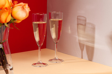 Close up photo of champagne glasses with roses in a vase