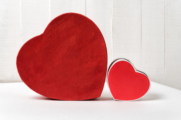Big and small red heart shaped boxes on table. Side view. Valentine's Day