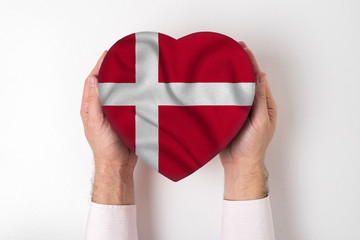 Flag of Denmark on a heart shaped box in a male hands. White background