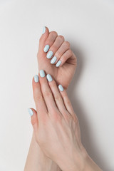 Female hands with delicate blue manicure. Gel Polish. White background. Verrical frame