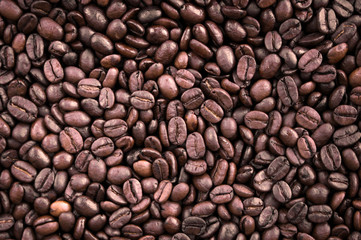 Mixture of different kinds of fresh roasted brown coffee beans in dark tones