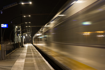 Blurred train by motion at night at station Arnhem south, Netherlands