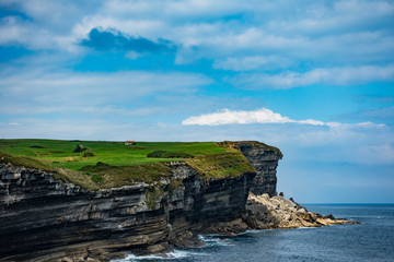 Acantilados rocosos junto al mar del bolao con gran prado verde con una casa y cielo con ligeras nubes