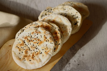Fladenbrot Pita gebacken mit Swarzkümmel auf Holzbrett mit Stoffserviette und Holzuntergrund
