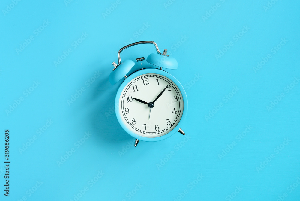 Wall mural blue vintage alarm clock on blue background. top view. flat lay