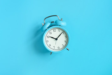 Blue vintage alarm clock on blue background. Top view. Flat lay