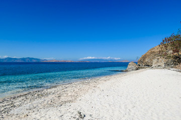 Fototapeta na wymiar A panoramic view of idyllic white sand beach in Komodo National Park, Flores, Indonesia. Beach is gently washed by waves. Island has scarcely any plants on it. Idyllic location. Serenity and calmness