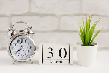 March 30 on a wooden calendar next to the alarm clock.Calendar date, holiday event, or birthday