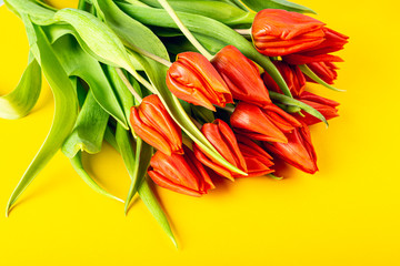 Yellow background with orange tulips, Easter. Birthday, mother day greeting card concept with copy space. Top view, flat lay.